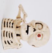 MONEY BOX: A 20th century cast iron hand painted halloween style money box in the form of a skull.