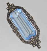 A 1930s Art Deco silver brooch with central blue glass surrounded by marcasite in a geometric