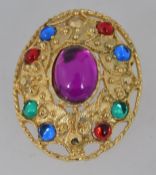A vintage yellow metal brooch with glass