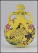 A Chinese enamel painted perfume bottle - moon flask having yellow ground and decorated with