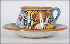 A stunning French faience Art Nouveau cup and saucer having elaborate hand painted decoration of a