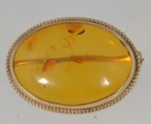 A vintage 9ct gold hallmarked brooch pin set with a single amber cabouchon in a bezel rope twist