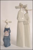 A Lladro porcelain figure group modeled as two Nun's in habits 33cm tall,