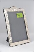 A contemporary silver picture / photo frame with reeded and oak leaf decoration having an easel
