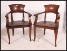 2 Industrial hardwood office fan back armchairs having panel seats being raised on squared legs.