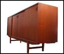 A 1970's Danish teak sideboard dresser raised on tapering legs with a series of sliding doors and