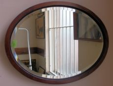 A mahogany Edwardian oak framed bevelled glass oval mirror with back panel in place