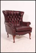 A stunning red leather oxblood Chesterfield wingback armchair raised on cabriole legs with button