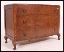 A 1930's Art Deco oak low bow front chest of drawers raised on cabriole legs with pad feet having