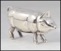 A sterling silver vesta case in the form of a pig with hinged head and striker to the base.