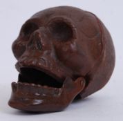 A cast iron casting of a skull, painted in brown, with a moving jaw bone.