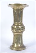 A Chinese brass gu vase of cylindrical form with geometric designs and symbols,