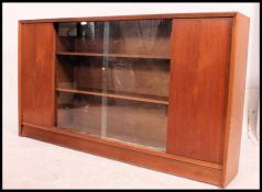 A retro 1970's teak wood Danish influence library bookcase cabinet having sliding glass doors with
