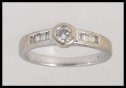 An 18ct white gold ring set with central round cut diamond with baguette diamond shoulders.