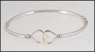 A silver contemporary ladies twin heart bangle / bracelet stamped 925.
