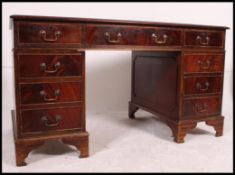 A Georgian style mahogany twin pedestal writing table desk raised on plinth bases to the drawer