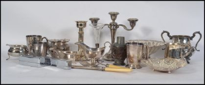 A collection of silver plated items to include teapot, creamer, candlesticks, beakers, tankards,