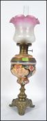 An early 20th century brass and painted ceramic oil lamp,