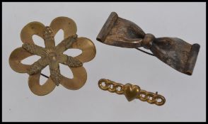 Three early 1920s gold tone brooches all with c clasp one in the form of a flower ,
