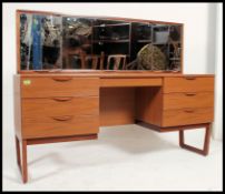 A 1970's retro teak veneer dressing table raised on angular supports having a wide low body with
