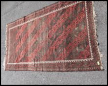 An early 20th century handwoven Persian rug with red ground - black wave design to centre and wavey