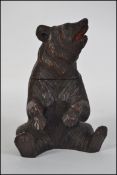 A good early 20th century Black Forest wooden seated bear, possibly an inkwell having hinged top.
