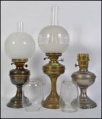 A collection of early 20th century brass oil lamps complete with the glass flues to each,