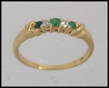 A gold ring testing 18ct set with alternating emeralds and diamonds in a prong setting. Size O.5.