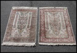 2 Islamic silk and wool machine woven prayer rugs, each with tassled ends having central mihrab.