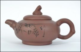 A Chinese Terracotta King-Xi teapot with decorative design having lid and markings to the base