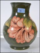 A large Walter Moorcroft pattern tubeline decorated vase on green ground with pink flowers,