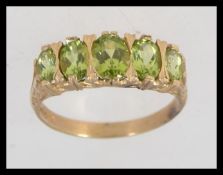 A 9ct gold peridot inset 5 stone ring of graduating sizes set on a decorative shank.