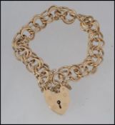 A 9ct gold double hoop link ladies bracelet and heart locket complete with safety chain being