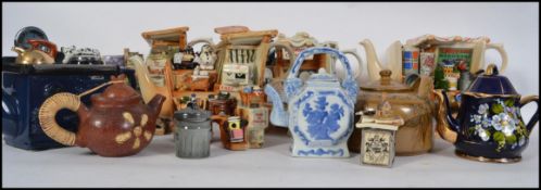 A collection of ceramic novelty teapots together with others including cottages etc ( see