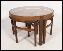 A retro 1970's Nathan teak and glass quartetto nest of table being raised on shaped legs with 4