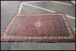 An early 20th century Persian handwoven rug having red / blue ground with medallions to centre