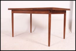 A 1970's Danish teak wood refectory drawer leaf dining table being raised on turned legs with