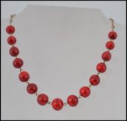A vintage Art Deco cherry red bead necklace with rolled gold links and hook clasp in a vintage
