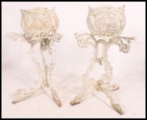 Two white painted cast iron upcycled garden architectural plant stands with tripod legs.