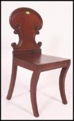 A Victorian mahogany hall chair raised on sabre supports with panel seat and armorial shield back