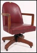 A mid century retro red vinyl and oak office industrial swivel chair.