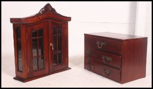 A 20th century table top hard wood chest of drawers along with a similar wall hanging glazed