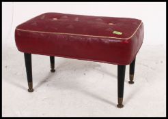 A vintage mid century dressing table stool / pouffe having a red vinyl button back pad being raised