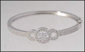A ladies contemporary silver bangle adorned with cz stones having ribbon / daisy head centre