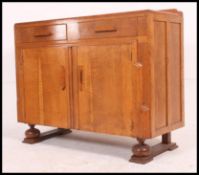 A 1930's Art Deco oak sideboard raised on shaped and slatted legs base with twin cupboard doors and
