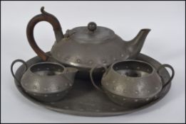 An Arts & Crafts pewter 4 piece tea service comprising teapot, sugar bowl, creamer and tray.