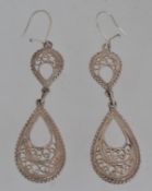 A pair of white metal drop earrings with