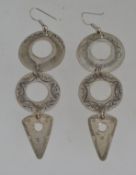 A pair of white metal drop earrings with
