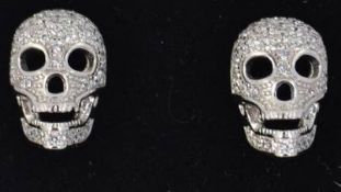A pair of designer 925 silver stud earrings in the form of skulls pave set with CZ stones with push