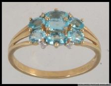 A hallmarked 9ct gold dress ring with oval cut blue topaz in a lattice setting with diamond accent
